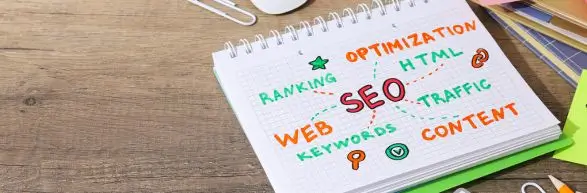 Reklama 2 Zeszyt z kolorowymi hasłami związanymi z SEO – takimi jak content, keywords, web, ranking – symbolizujący strategię promocji i widoczności w internecie