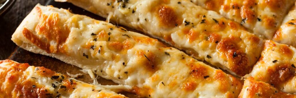 Doradzamy, jak zrobić chleb czosnkowy z serem lepszy niż w restauracji 2 Podłużne kawałki pieczywa zapiekane z serem. Obrazek w artykule Doradzamy, jak zrobić chleb czosnkowy z serem lepszy niż w restauracji